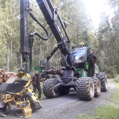 grüne Forstmaschine auf Waldweg mit 2 Personen